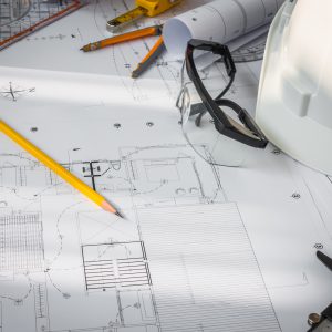 Construction plans with White helmet and drawing tools on blueprints